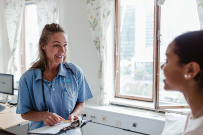 Smiling female nurse talking with patient in hospital