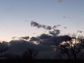 Low angle view of silhouette trees against cloudy sky