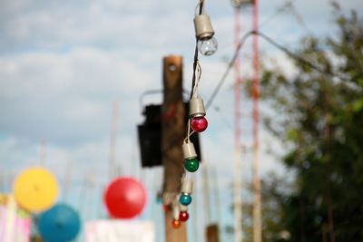 Low angle view of lighting equipment hanging against trees