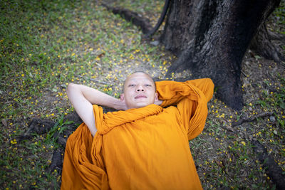 High angle view portrait of monk lying on grass