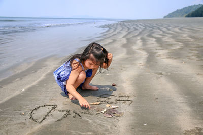 Full length of girl carving on sand at beach