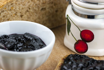 Close-up of preserves with bread and jar on wooden tray