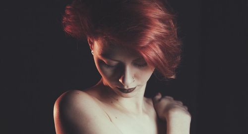 Close-up of redhead woman over black background