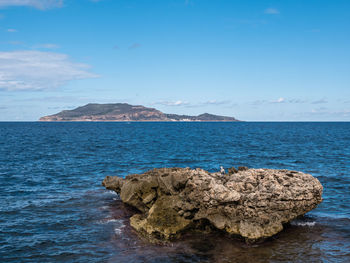Rocks on sea shore against blue sky