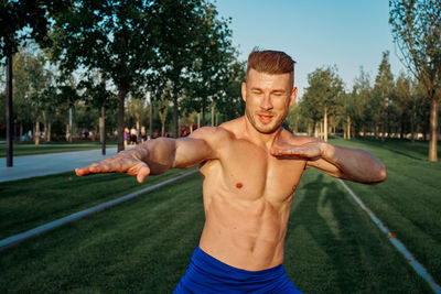 Portrait of young man exercising on field