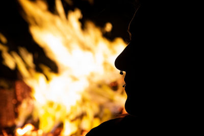 Close-up portrait of silhouette man against fire at night