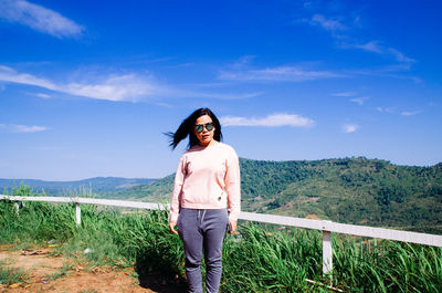 Portrait of young woman standing on observation point against sky