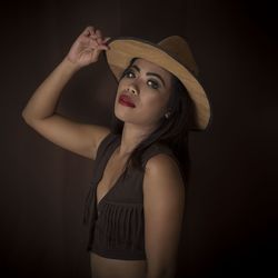 Portrait of woman wearing hat against black background