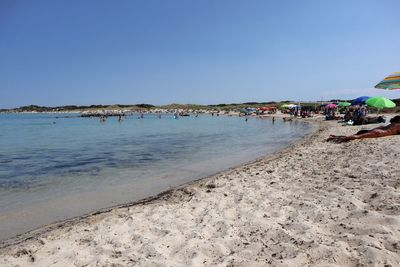 People on beach against clear sky