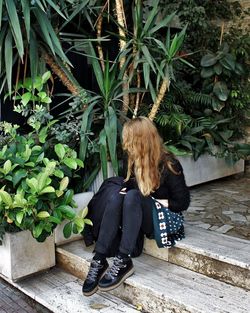 Rear view of woman sitting with plants