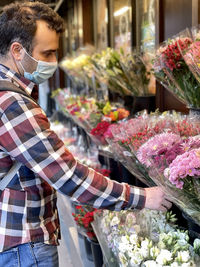 A young man wearing a mask is shopping for flowers 