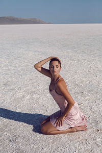 Woman sit on a dried up salt lake in a pink dress in the crimea