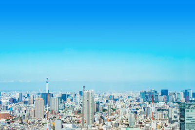 Aerial view of modern buildings in city against blue sky