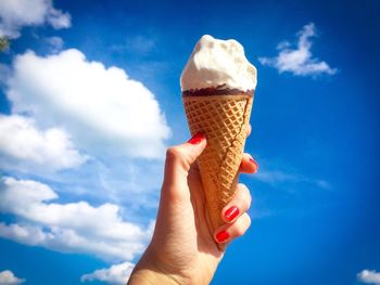 Midsection of woman holding ice cream against blue sky