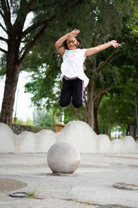 Outdoor portrait of a cute malaysian little girl with long hair jumping.