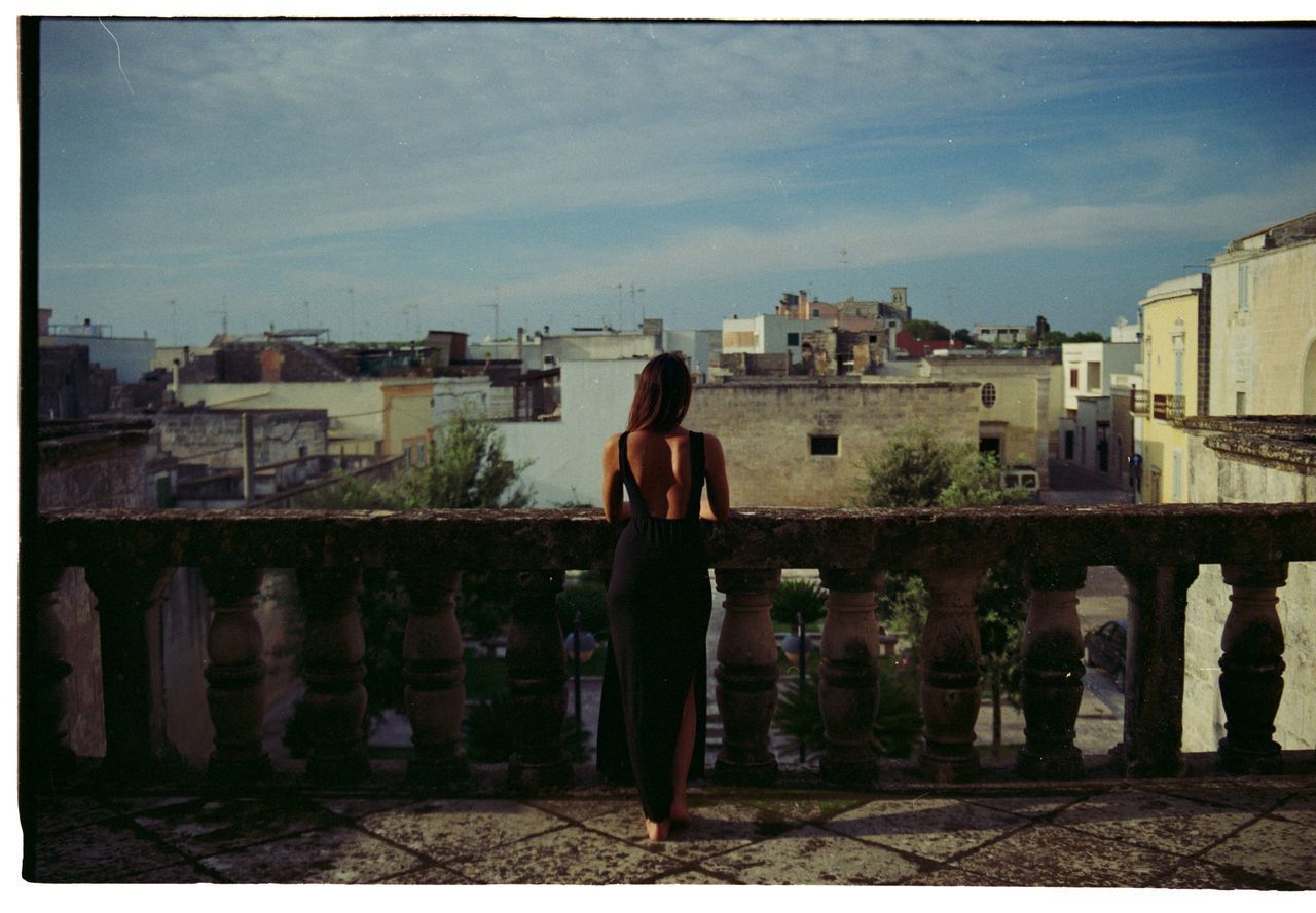 WOMAN STANDING BY CITYSCAPE