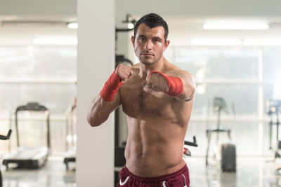 Full length of shirtless man standing against wall