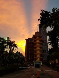 Building by street against sky at sunset