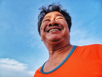 Low angle view of smiling mature man against sky