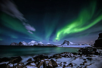 Scenic view of sea and mountains against sky at night