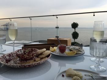 Food with champagne flutes on table at outdoor restaurant by sea