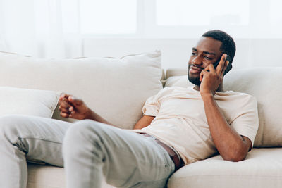 Young woman using phone while lying on bed at home