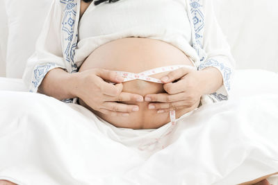 Midsection of woman lying on bed