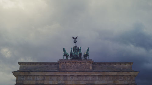 Low angle view of brandenburg gate against cloudy sky