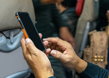 Midsection of man using mobile phone in bus