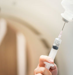 Cropped hand of doctor holding syringe at hospital