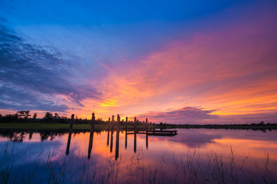 Scenic view of lake against dramatic sky during sunset