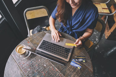 High angle view of woman using mobile phone while sitting on table