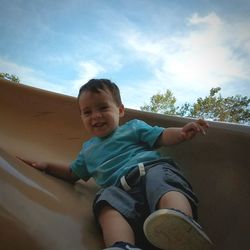 Portrait of boy playing in playground against sky
