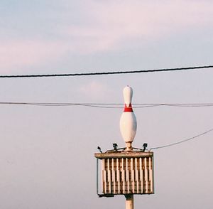 Low angle view of bird perching on cable against sky