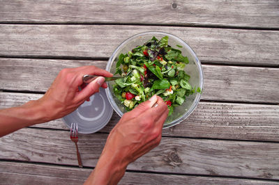 Directly above shot of hand mixing salad in bowl on table