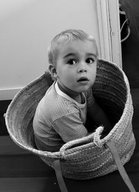 High angle portrait of cute boy sitting in bucket at home