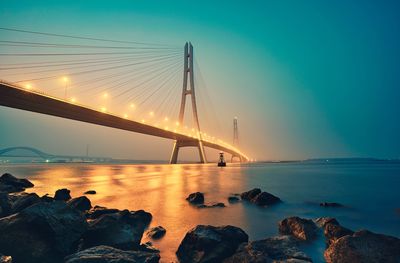 Suspension bridge over sea against sky