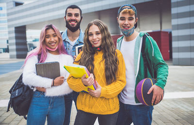 Cheerful friends carrying book outdoors