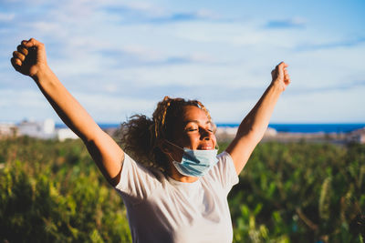 Full length of woman with arms raised against sky