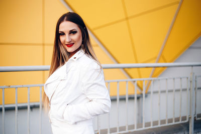 Portrait of woman standing against railing