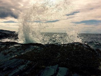 Waves splashing on shore against sky