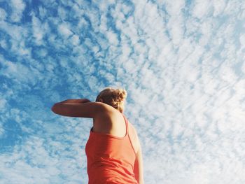 Low angle view of woman standing against blue sky