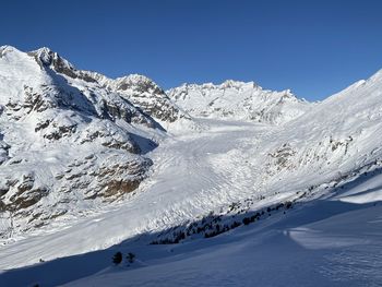 Scenic view of snowcapped mountains against clear blue sky