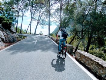 Rear view of man riding bicycle on road