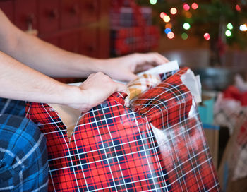 Midsection of woman opening gift at home