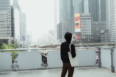 Rear view of man standing at terrace in city