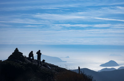 Men standing on rock against sky