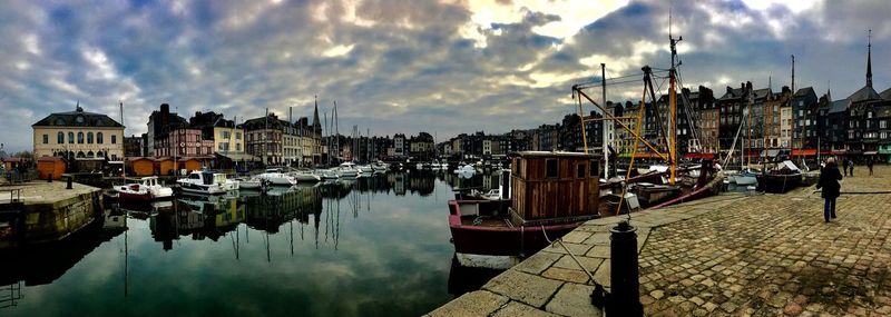 Boats moored at harbor against sky