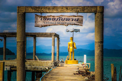 Information sign on pier over sea against sky