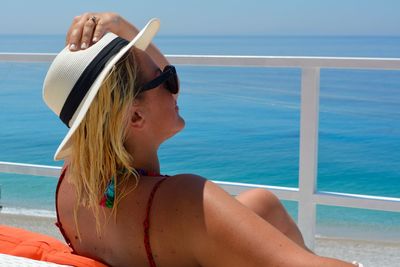 Woman wearing sunglasses while sitting at beach